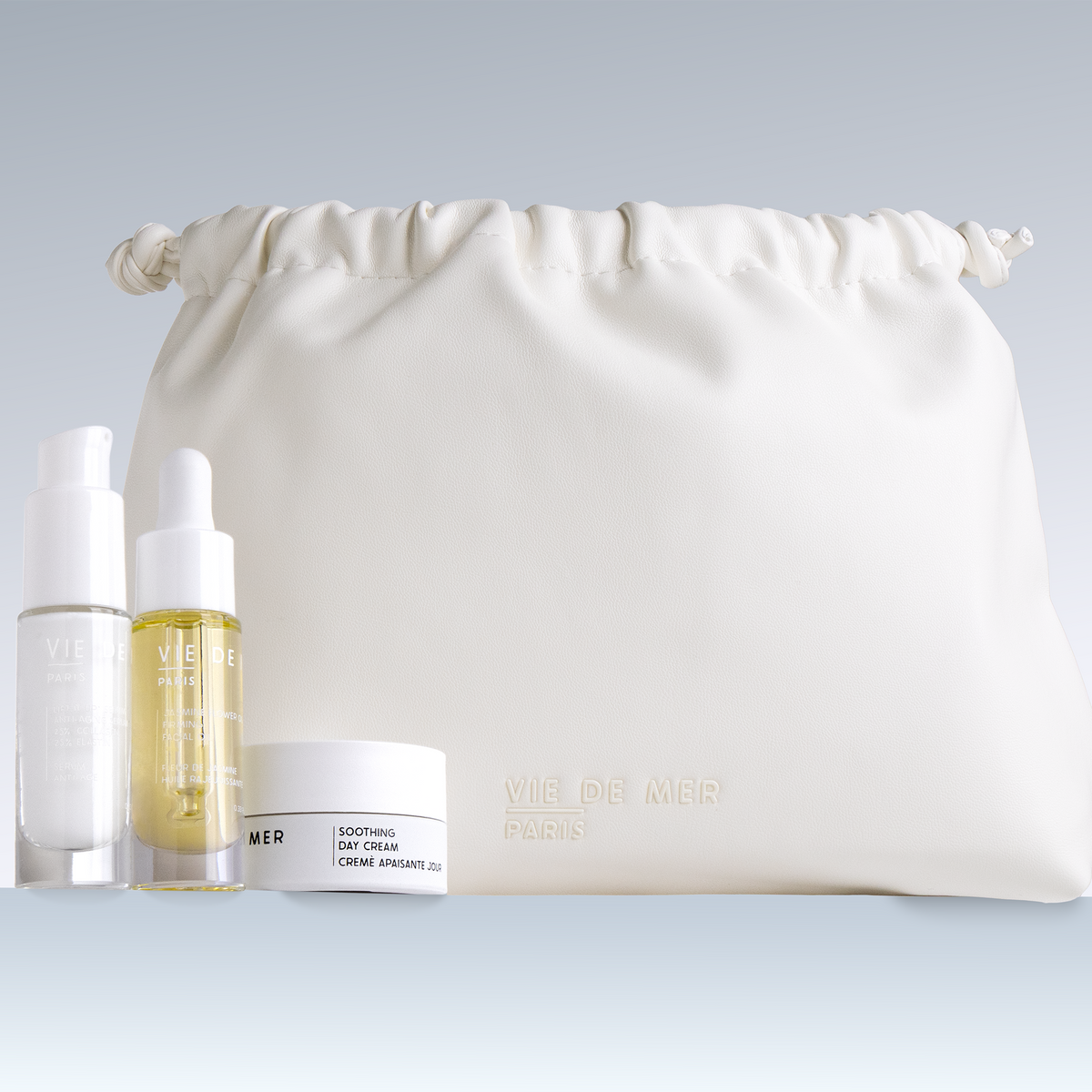 Skincare products including bottles and a cream jar with a white drawstring bag on a light gray background.
