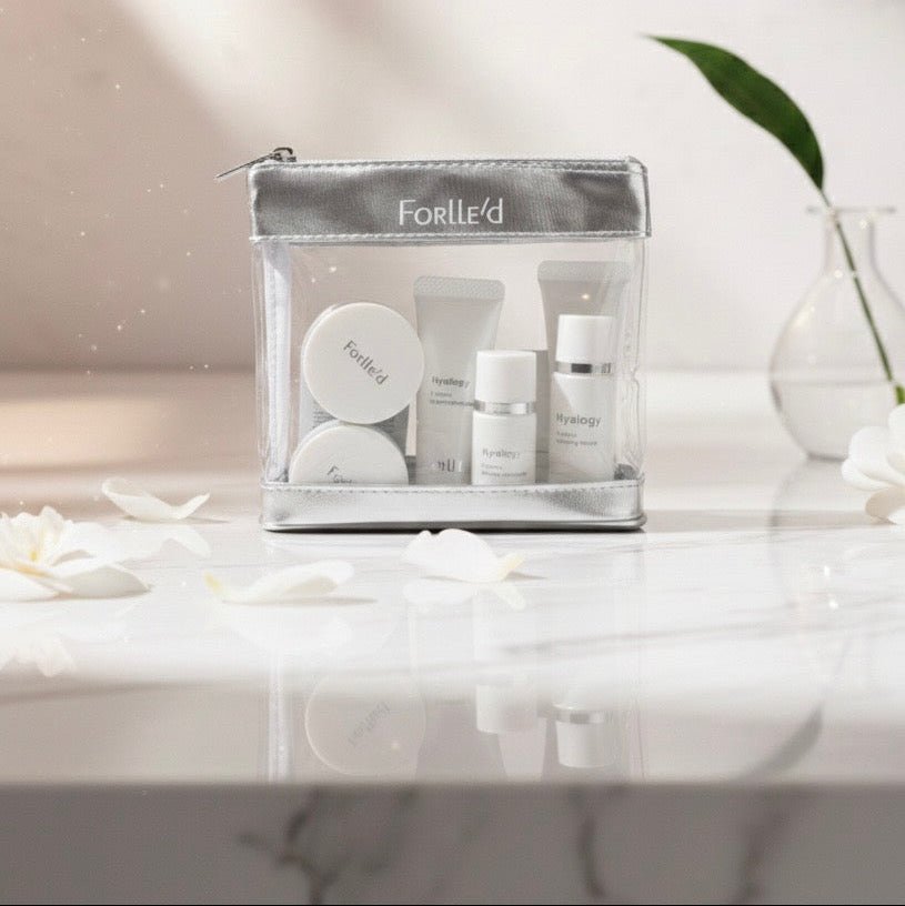 Clear cosmetic bag with skincare products on a marble surface