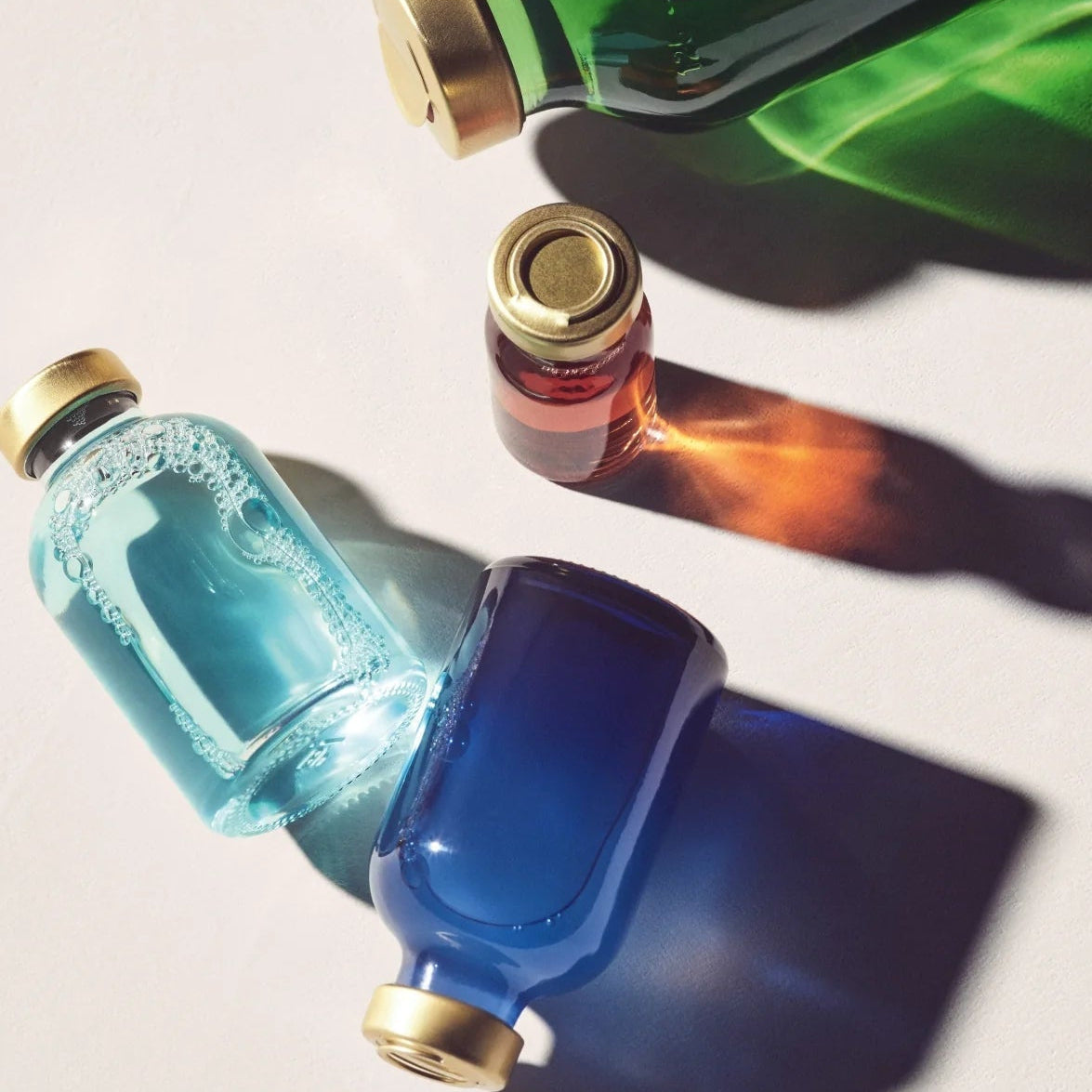 Three glass bottles with gold caps on a light background