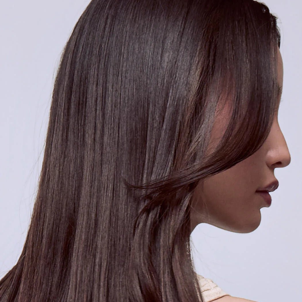 Side profile of a person with long, dark brown hair on a light gray background