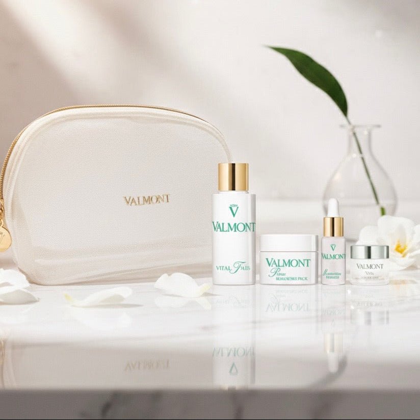 Valmont skincare products on a white surface with a beige pouch and decorative elements.